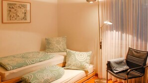 Una habitación pequeña y acogedora con una cama, una silla y una lámpara de pie.