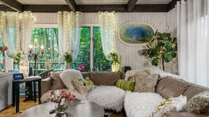 A cozy living room with a large sectional sofa, a round coffee table, and a view of the outdoors through large windows.
