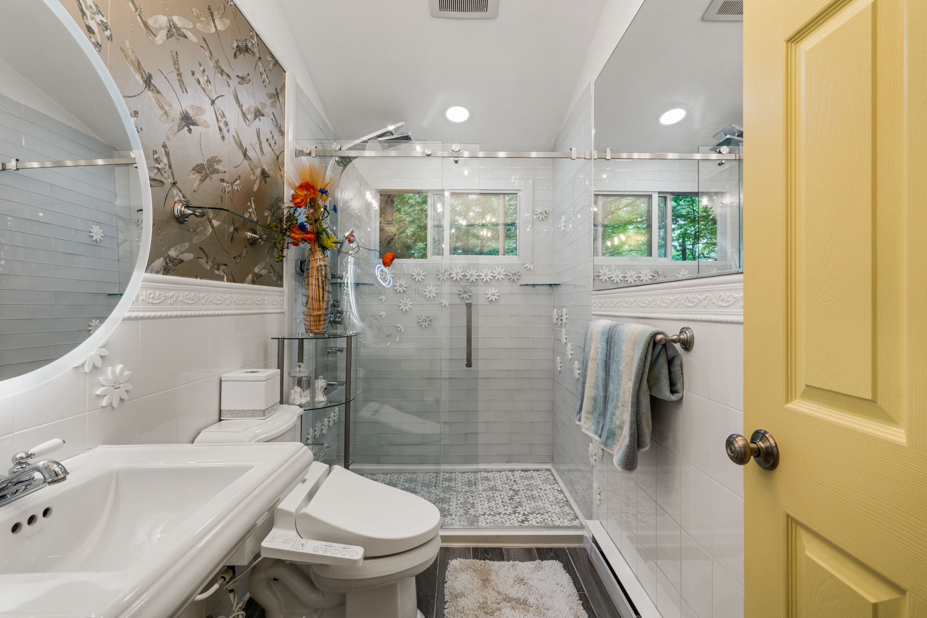 A modern bathroom with a shower, toilet, sink, and a large mirror.