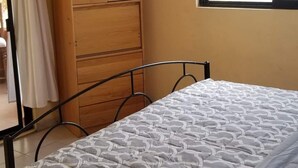 A bedroom with a bed, a wardrobe, a window, and a fan. - Las Palmas (Ejido Plutarco Elias Calles)