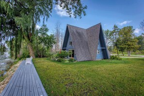 Una casa moderna con techo inclinado, una terraza y un patio cubierto de césped.