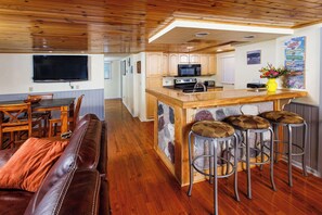 Una cocina con armarios de madera, microondas e isla de piedra con taburetes de bar.