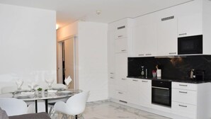 A modern kitchen with white cabinetry, a black countertop, and a marble floor. - App. 704 by Interhome (Bissone)