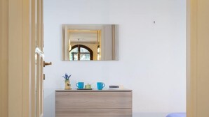 Een slaapkamer met een houten dressoir, een spiegel en een bed met een blauwe deken.