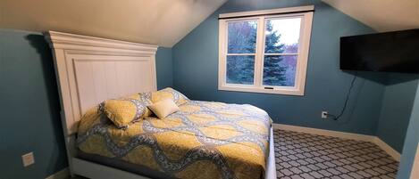 Une chambre à coucher avec un lit, une fenêtre et un téléviseur fixé au mur.