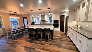 Una cocina moderna con una isla central, taburetes de bar y una mesa de comedor con sillas.