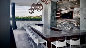 A modern kitchen with a long island, white bar stools, and a stone backsplash. - Great Comfort, Location, and Style Zona Romantica (AVIDA) (Puerto Vallarta)
