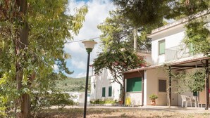 A white building with green shutters, a balcony, and a covered outdoor seating area. - Apartment in the Gargano Park (Vieste (FG))