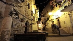 A narrow street with stone buildings, a bench, and a staircase leading to a door. - Apartment in the Gargano Park (Vieste (FG))