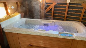 Un jacuzzi con panel de control, rodeado de paredes de madera y un banco.