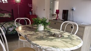 Un comedor con una mesa de mármol, sillas blancas y una planta en maceta.