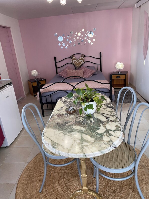 Une chambre à coucher comprenant un lit, des tables de chevet, un bureau et une table à manger avec des chaises.
