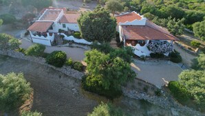 Villa blanca amb teulades vermelles, envoltada de vegetació i turons.
