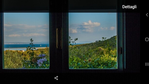 Habitació amb dues finestres que donen vistes a un paisatge costaner amb vegetació i una línia de costa llunyana.
