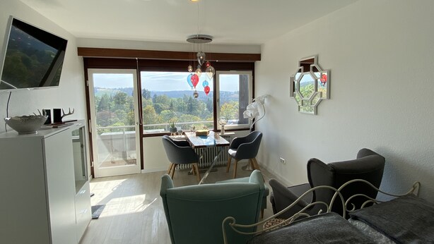 A modern room with a dining area, a bed, and a TV mounted on the wall. - Apartment Harzblick -neu Modernisiert- (Sankt Andreasberg)