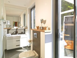 A modern bathroom with a large mirror, a toilet, and a sink. - Beach Cloud Luxury Apartment: Private Sauna, Pool, and Beach Chair | Terrace | Fireplace (Binz)