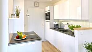 A modern kitchen with white cabinets, a black countertop, and a built-in oven. - Beach Cloud Luxury Apartment: Private Sauna, Pool, and Beach Chair | Terrace | Fireplace (Binz)