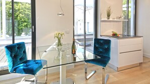 A modern kitchen with a glass dining table, two blue velvet chairs, and a white countertop. - Beach Cloud Luxury Apartment: Private Sauna, Pool, and Beach Chair | Terrace | Fireplace (Binz)