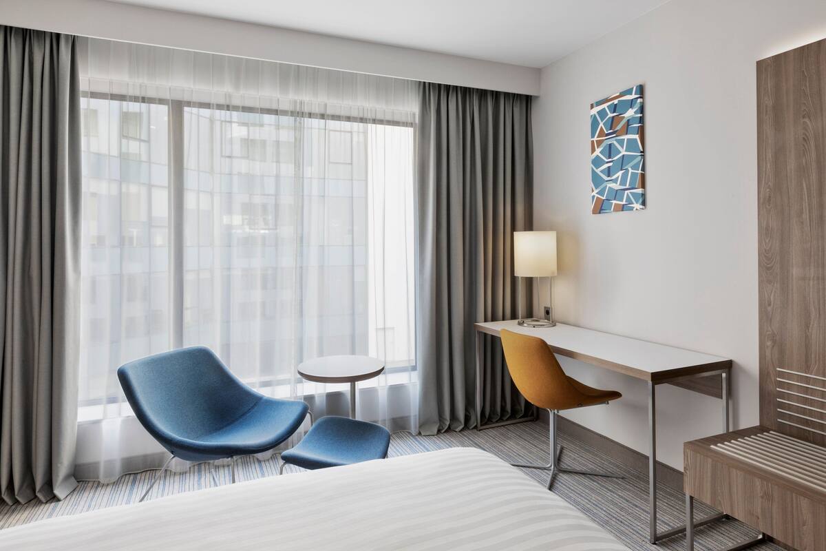 Une chambre d’hôtel avec un lit, un bureau, une chaise et une petite table.