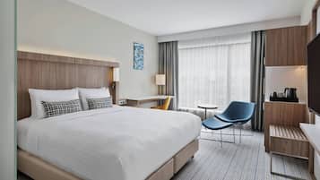 A hotel room with a large bed, a desk, a chair, and a TV.