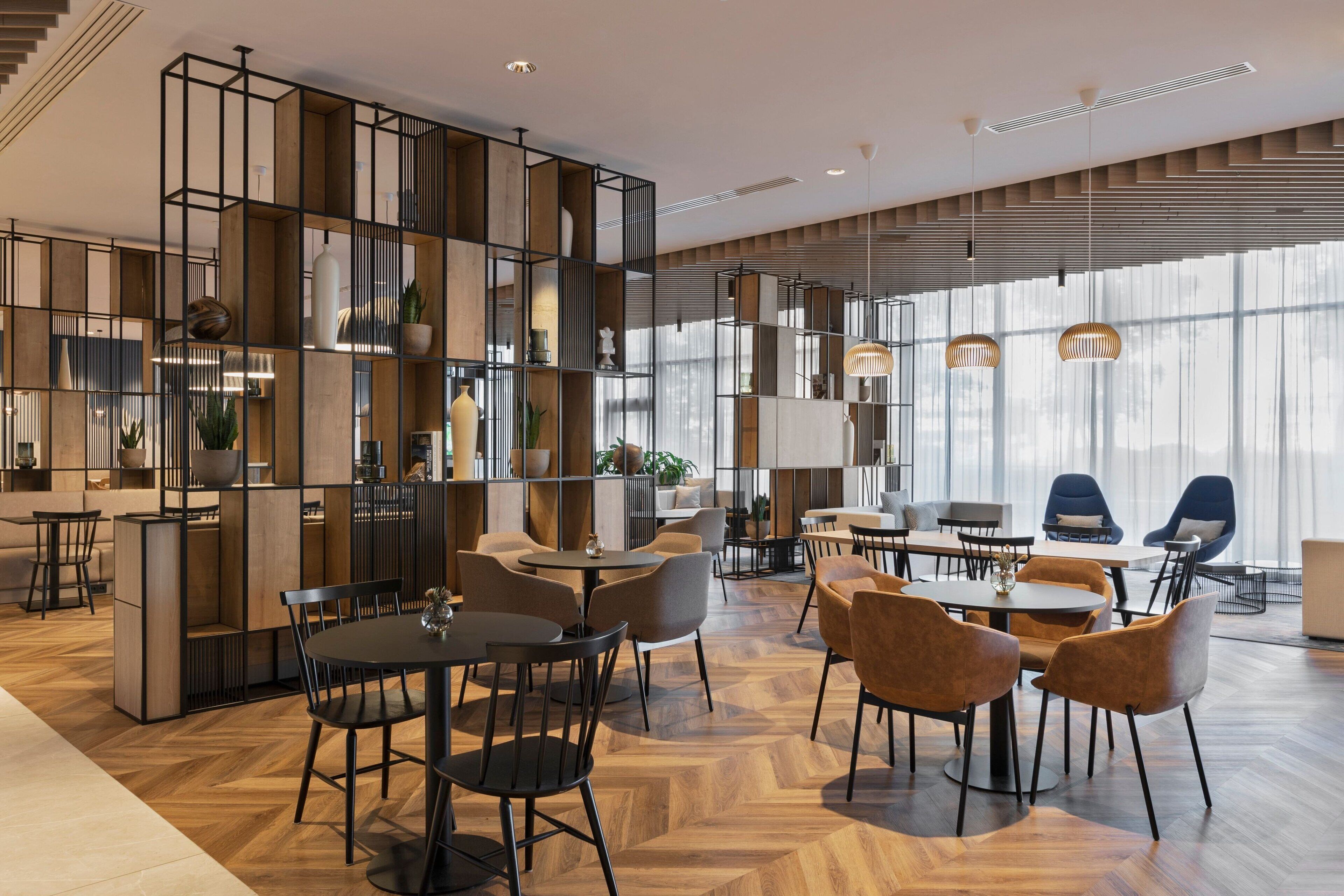Een modern interieur met een centrale eethoek, omringd door zitplaatsen en een keuken met een ingebouwde boekenkast.