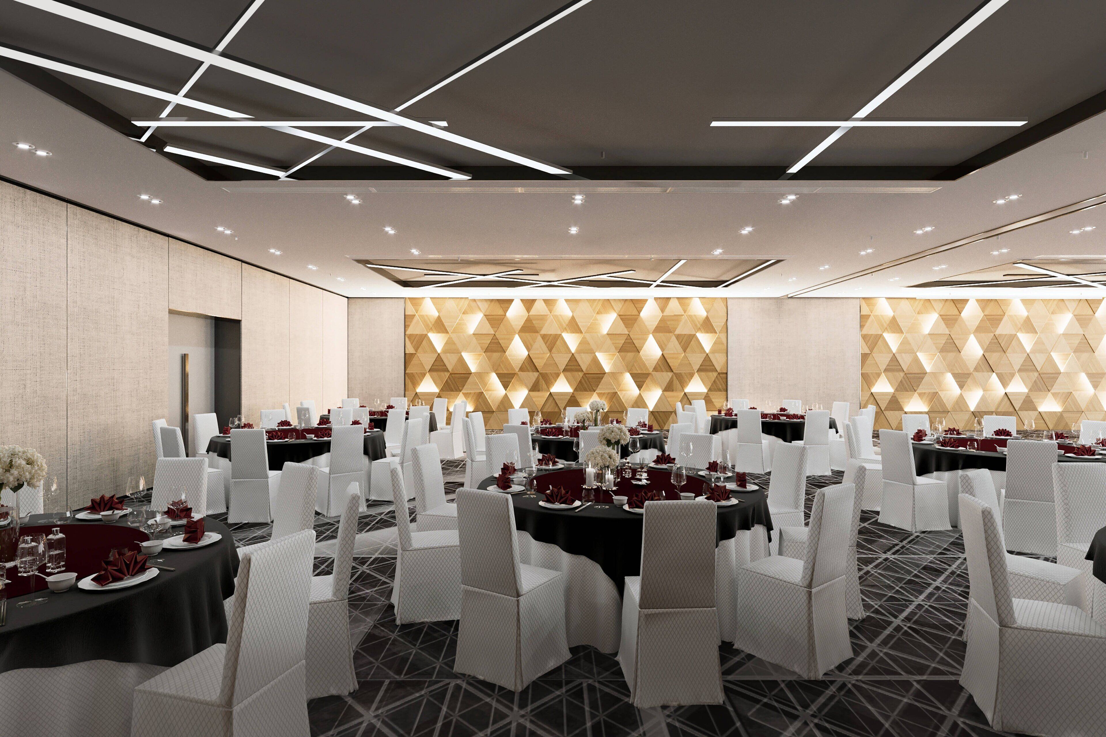 A banquet hall with round tables, white chairs, and a geometric patterned wall.