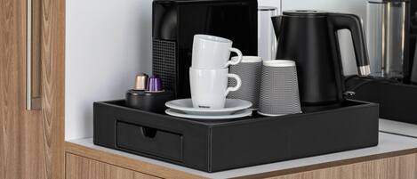 A kitchen counter with a coffee maker, a white cup, and a black mug.