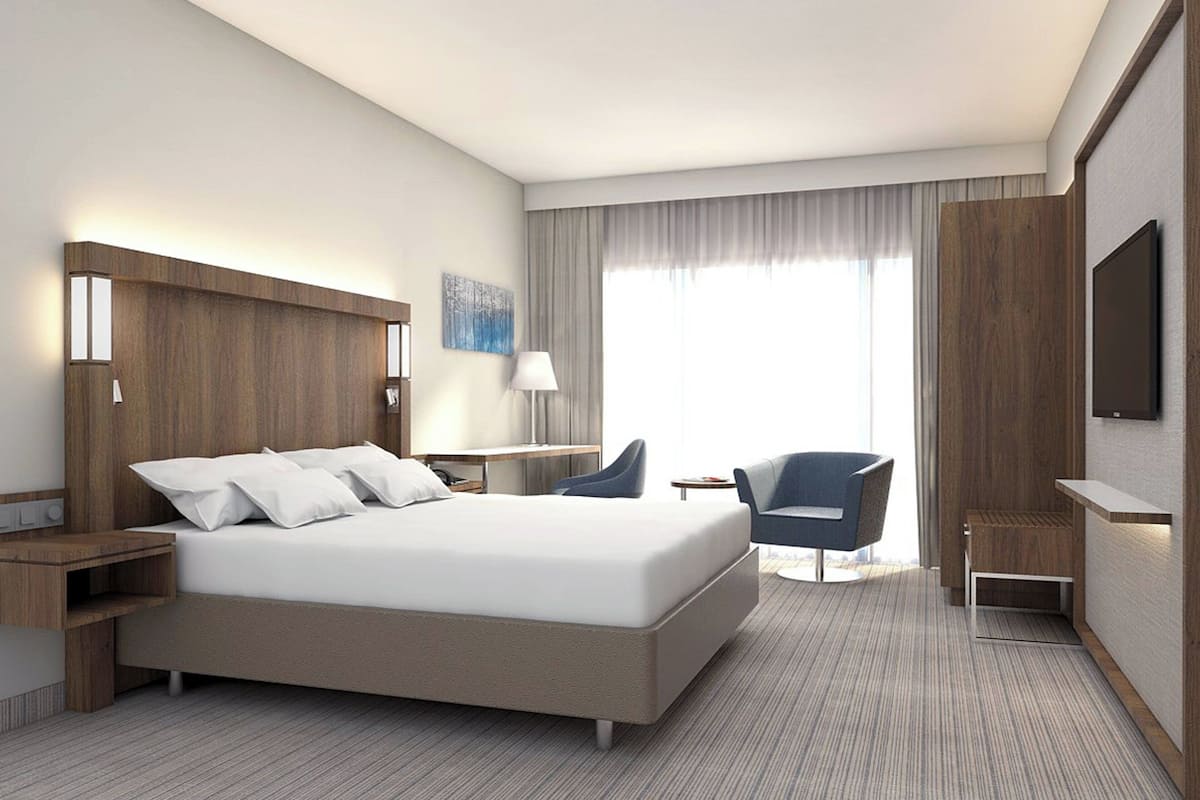 Une chambre d’hôtel moderne équipée d’un grand lit, d’un bureau, d’une chaise et d’un téléviseur.