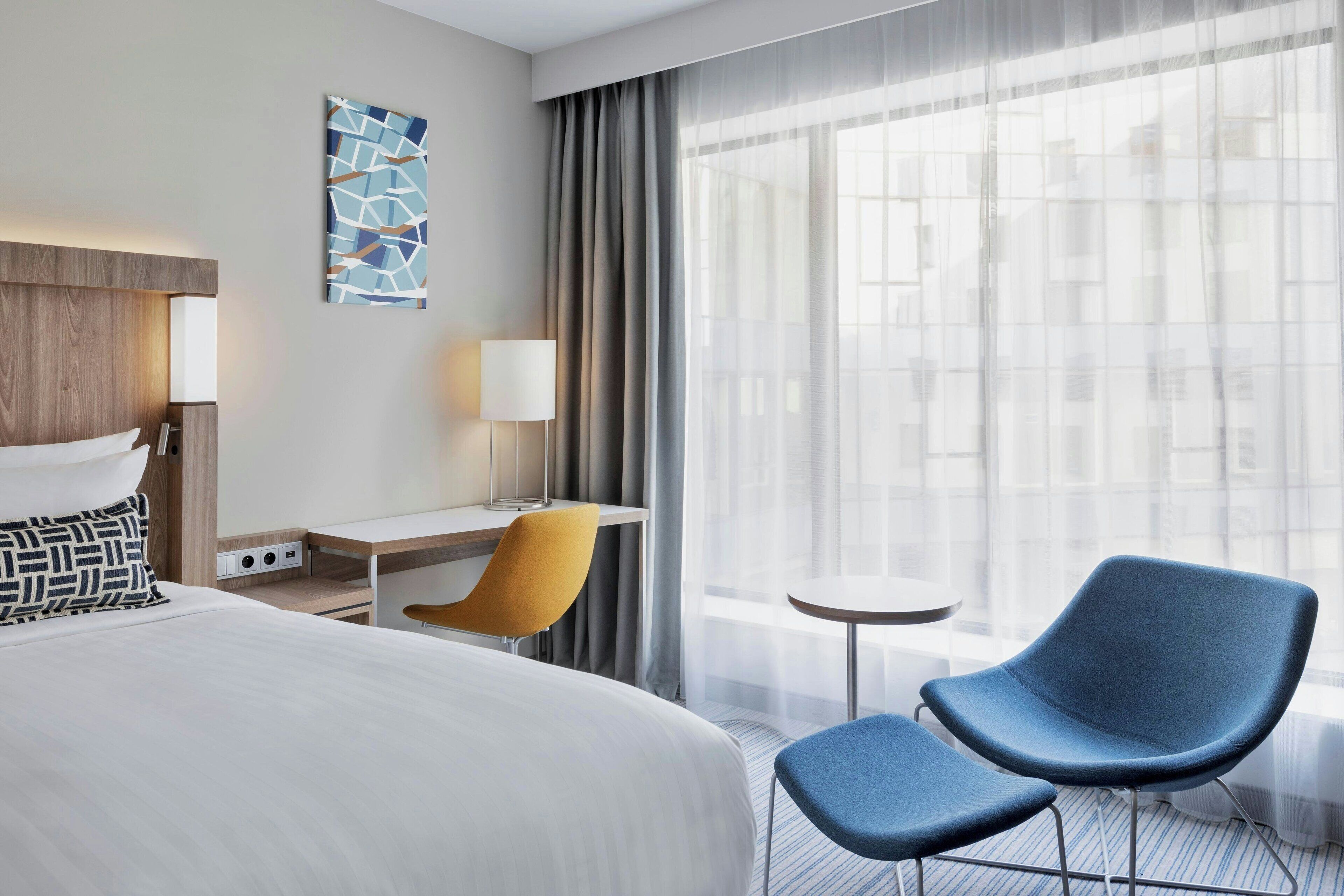 Une chambre d’hôtel avec un grand lit, un bureau, une chaise et une petite table.