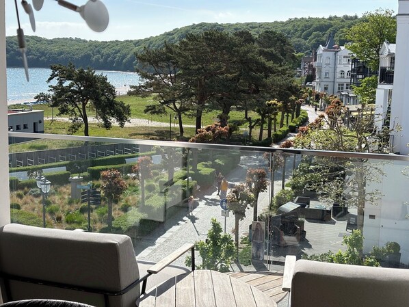A balcony with a view of a lake, trees, and buildings.
