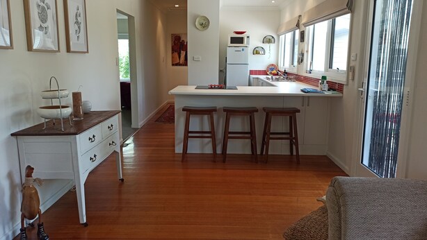 A modern kitchen with a central island, wooden stools, and a white countertop.