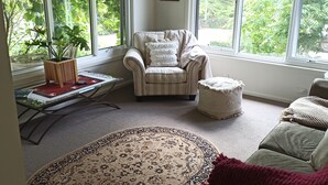 A spacious living room with a large window, a ceiling fan, a patterned rug, and a cozy seating area.