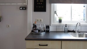 A kitchen with a black sign reading "WELCOME IN ONZE B&B 1-2-3", a window with a plant, and a sink. - Beautiful b&b/ vacation home located on a large garden surrounded by water. (Bovenkarspel)
