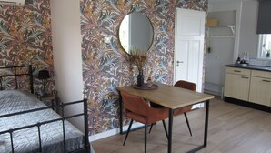 A bedroom with a bed, a bedside table, a mirror, and a wall with a tropical leaf pattern. - Beautiful b&b/ vacation home located on a large garden surrounded by water. (Bovenkarspel)