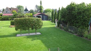 A well-maintained garden with a neatly trimmed lawn, a small tree, and a fence. - Beautiful b&b/ vacation home located on a large garden surrounded by water. (Bovenkarspel)