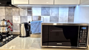 A modern kitchen with a stainless steel microwave, a kettle, and a coffee maker.