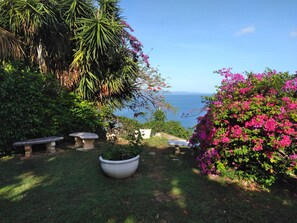 A garden with a view of the sea, stone benches, and a large planter. - Mobay Club Irresistible View (Montego Bay)