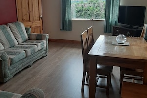 Una sala de estar con una mesa de comedor de madera, un sofá y un televisor.