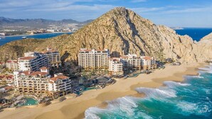 A coastal resort with multiple high-rise buildings, a beach, and a prominent rocky mountain in the background.