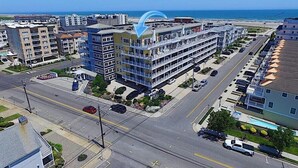 Un hôtel à plusieurs étages, doté de balcons, d’un parking et offrant une vue sur l’océan.