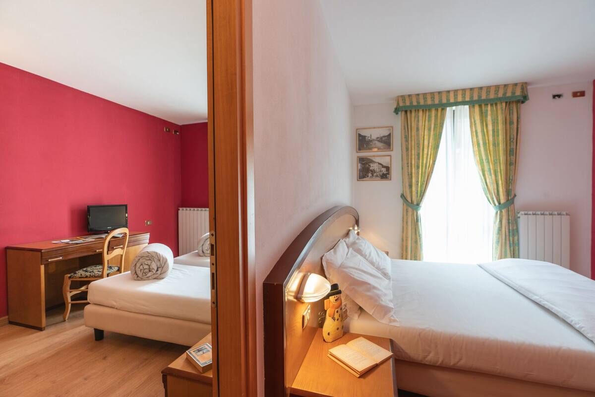 Un dormitorio con cama, mesita de noche, lámpara y un escritorio con silla.
