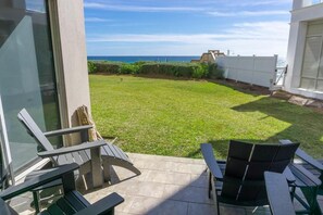 Un patio con mobiliario exterior, vistas al océano y una cerca blanca.