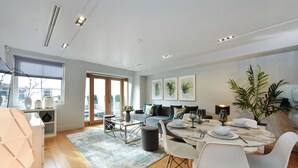 Un salon moderne avec un coin repas, de grandes fenêtres et une vue sur la ville.