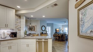 Una cucina moderna con mobili bianchi, lavastoviglie integrata e zona pranzo con tavolo e sedie in legno.