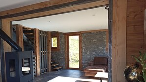 A modern interior with a stone wall, wooden beams, a fireplace, a staircase, and a cozy seating area. - Well-being of the old do **** (Ventron)