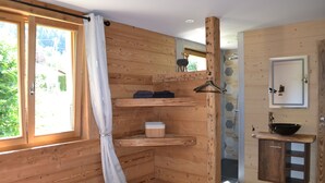 A wooden cabin room with a bed, shelves, a mirror, and a bathroom with a sink. - Well-being of the old do **** (Ventron)