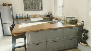 Uma cozinha com bancada de madeira, armários cinzas, pia e janela.