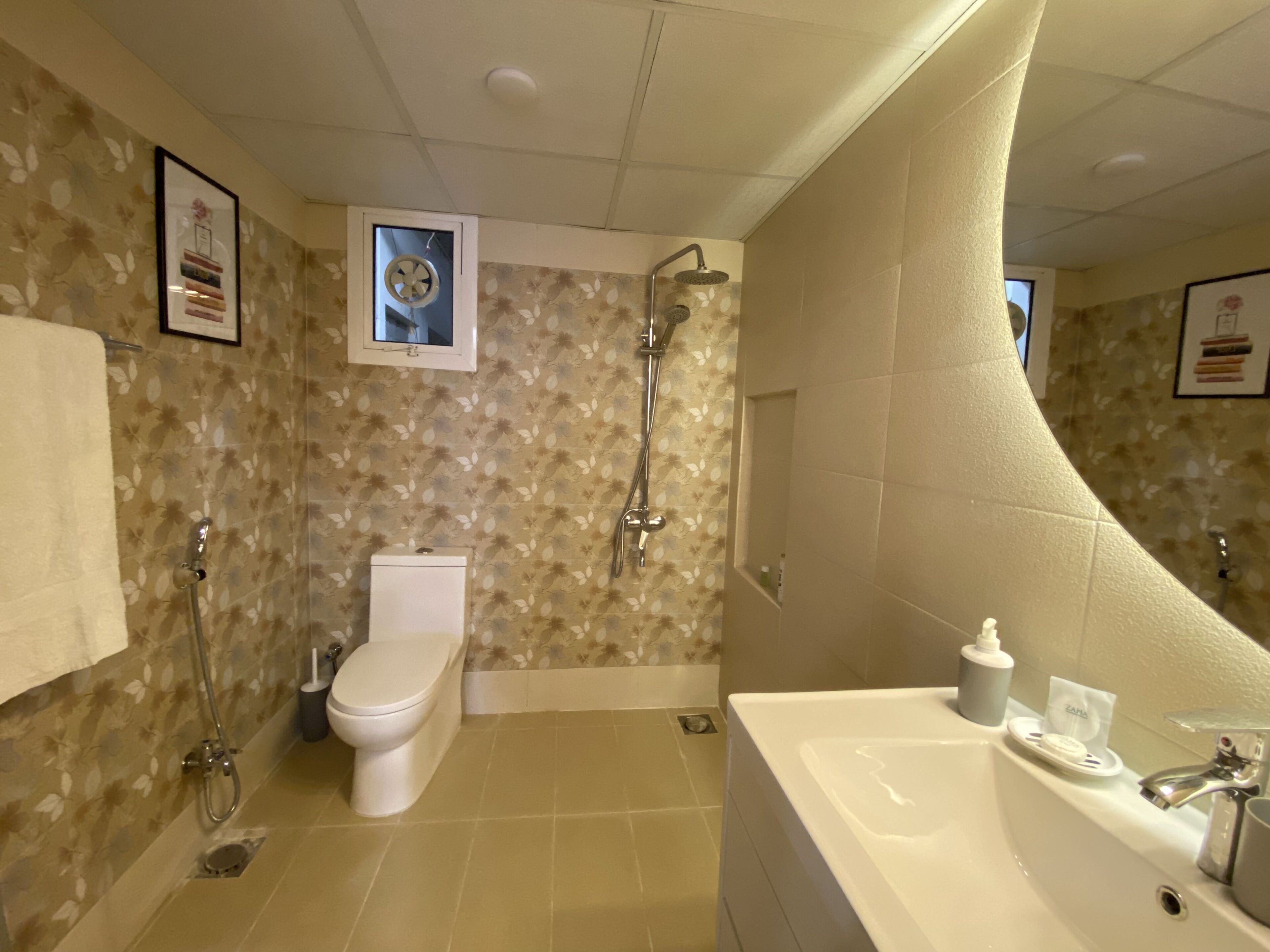 A bathroom with a shower, toilet, sink, and decorative wall tiles.