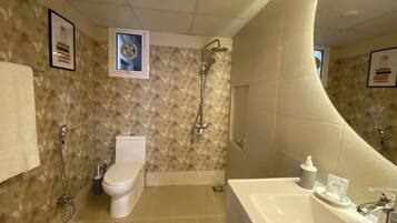 A bathroom with a shower, toilet, sink, and decorative wall tiles.