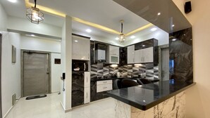 Una cucina moderna con piano di lavoro in marmo, elettrodomestici integrati e backsplash geometrico.